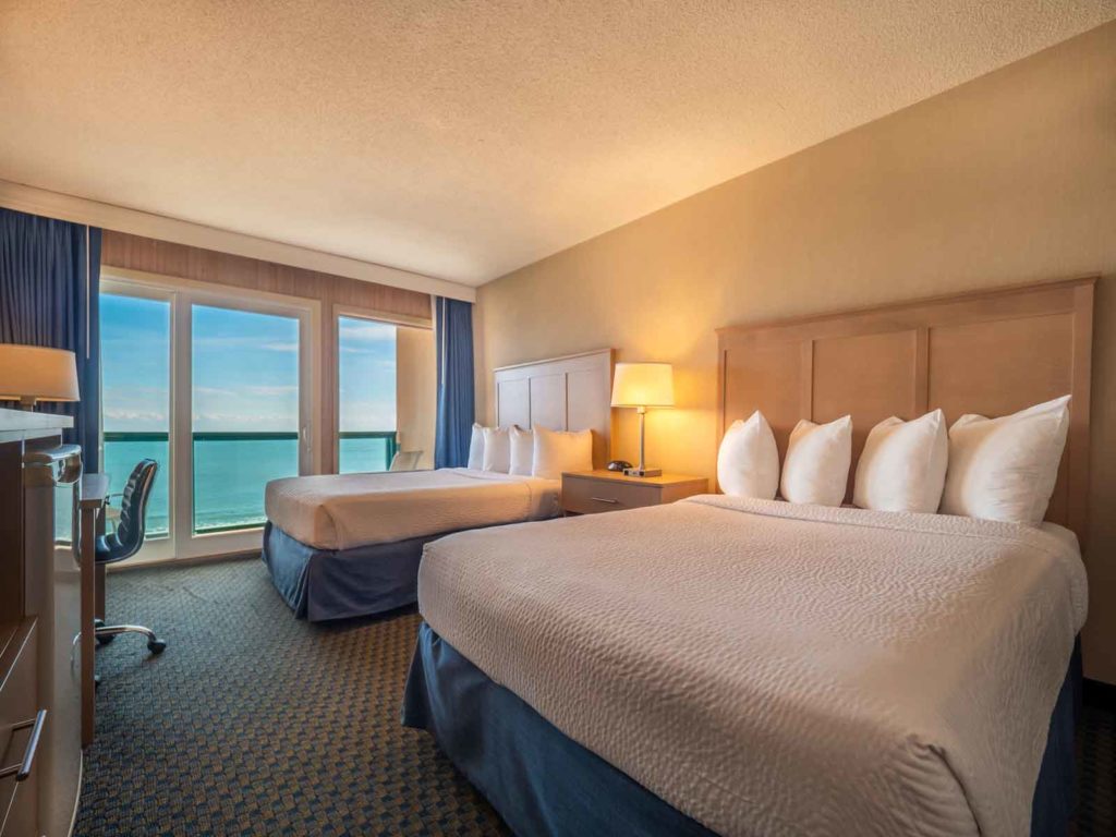 Two beds in hotel room overlooking beach and ocean