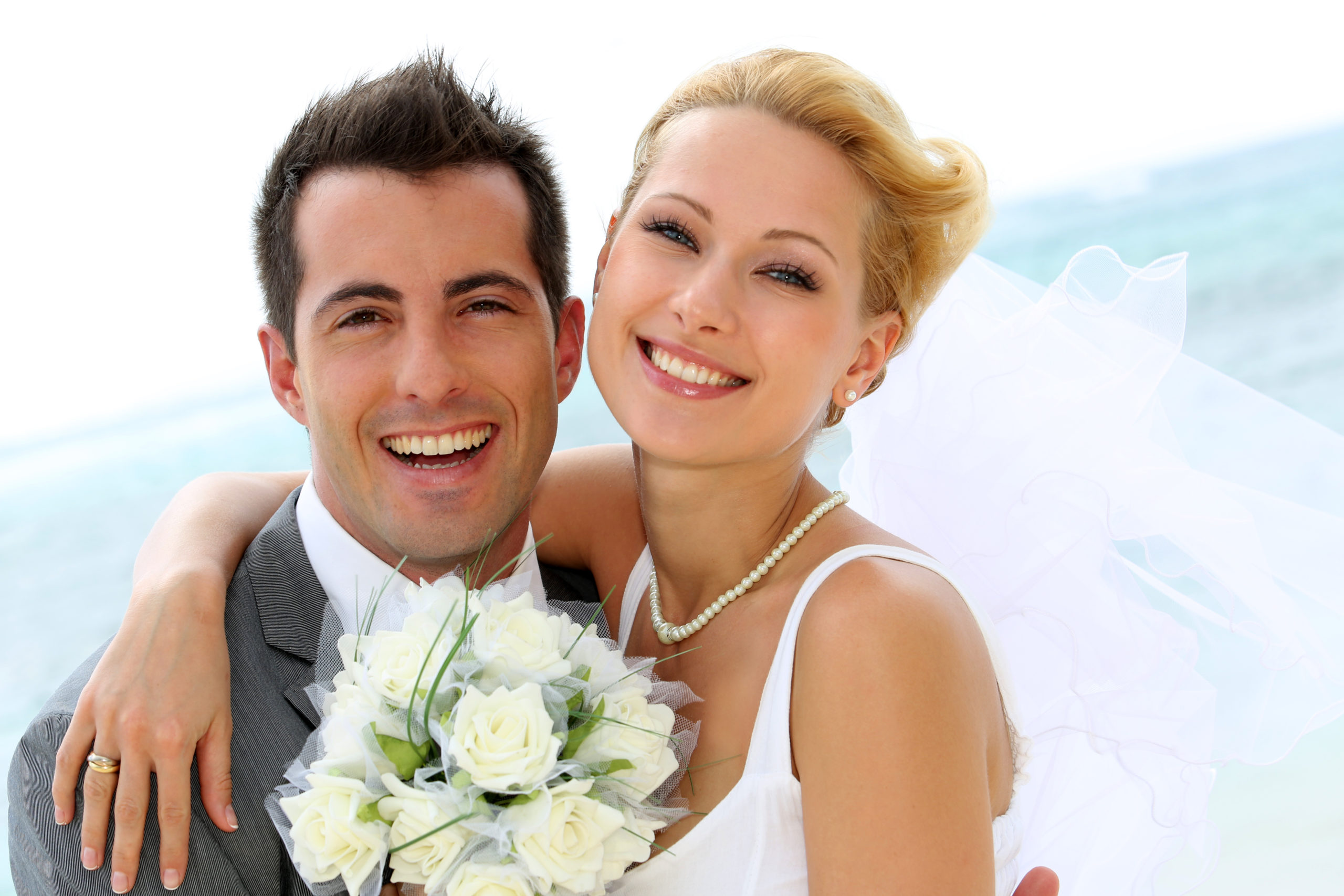 Bride and Groom holding each other smiling with white bouquet